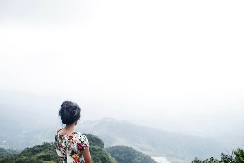 Woman Wearing Multicolored Floral Top Standing Near Mountain Under White Sky