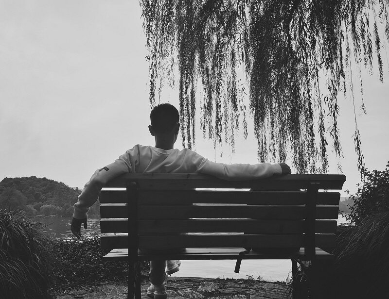 a man sitting on a bench under a tree