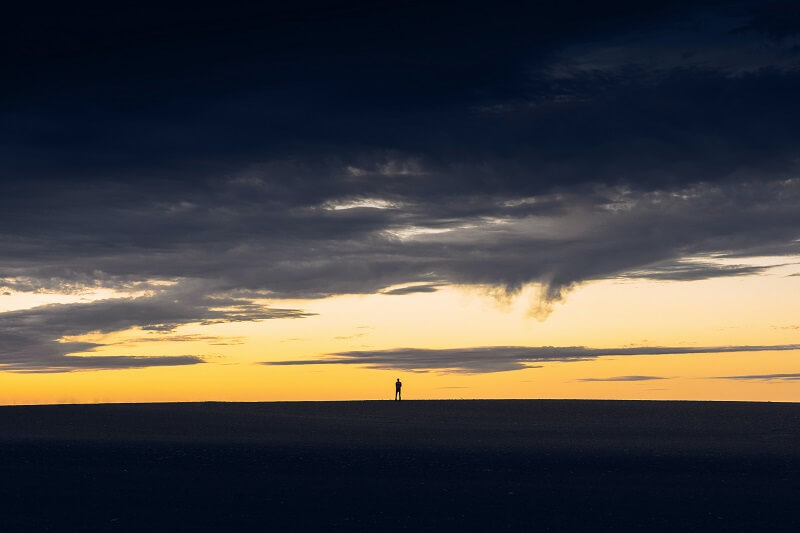 silhouette of person standing on hill during sunset