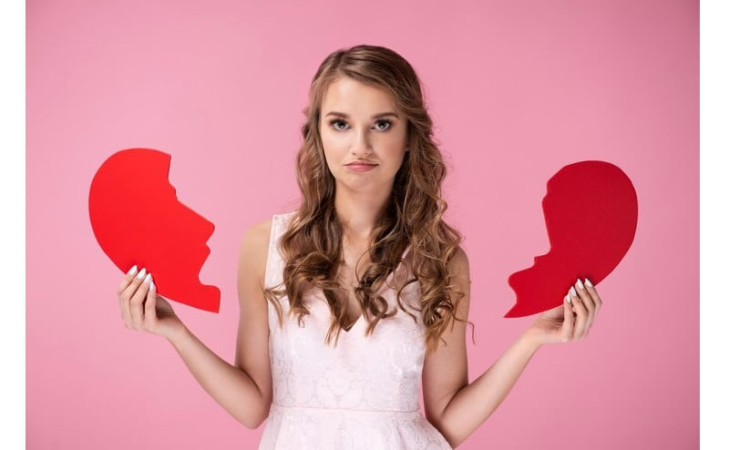 Portrait of sad woman holding broken heart