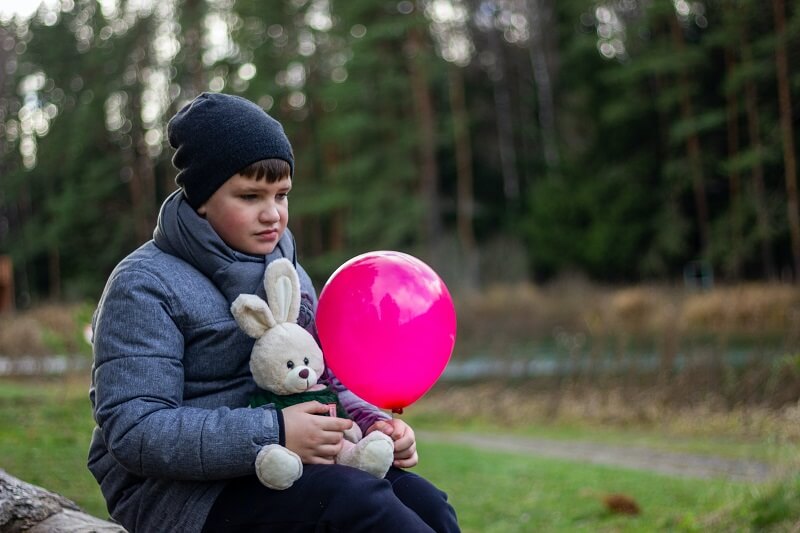 Boy in Jacket Sitting with Balloon and Teddy Rabbit