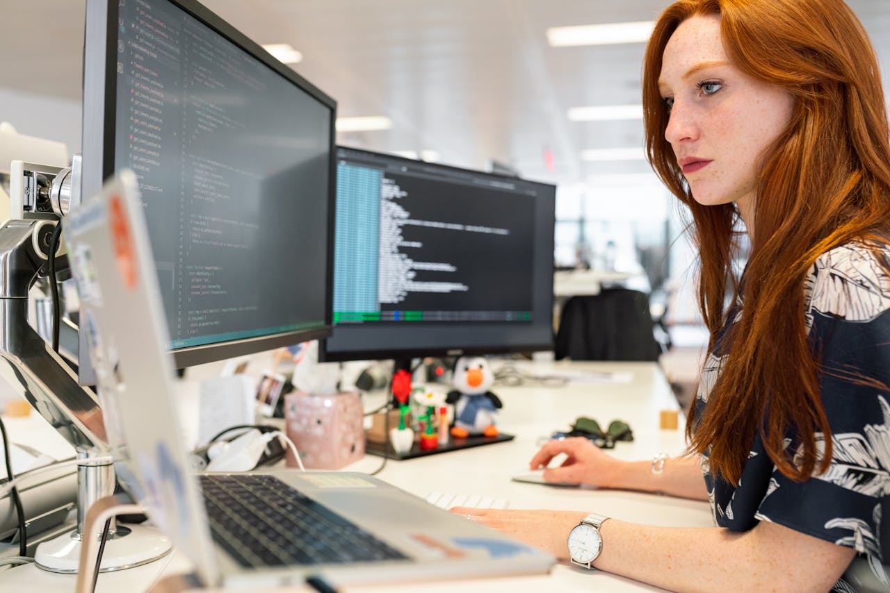 Mastering the First Impression: Your intriguing post title goes here A focused female software engineer coding on dual monitors in a modern office.